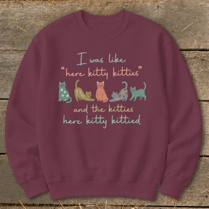 Burgundy sweatshirt with text "I was like 'here kitty kitties' and the kitties here kitty kittied" and illustrations of cats.