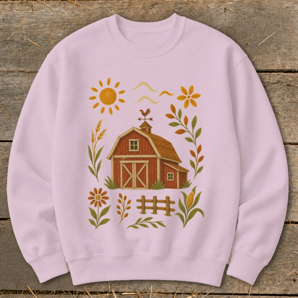 Pink sweatshirt with a red barn, sun, flowers, and fence graphic.