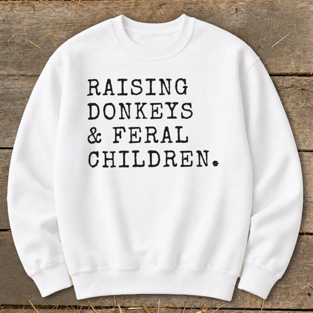 White sweatshirt with black text reading "RAISING DONKEYS & FERAL CHILDREN."