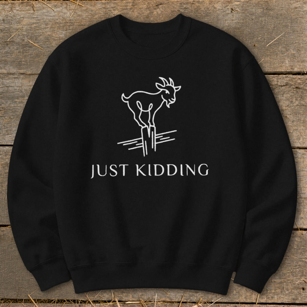 Black sweatshirt with white line drawing of a goat and "JUST KIDDING" text.