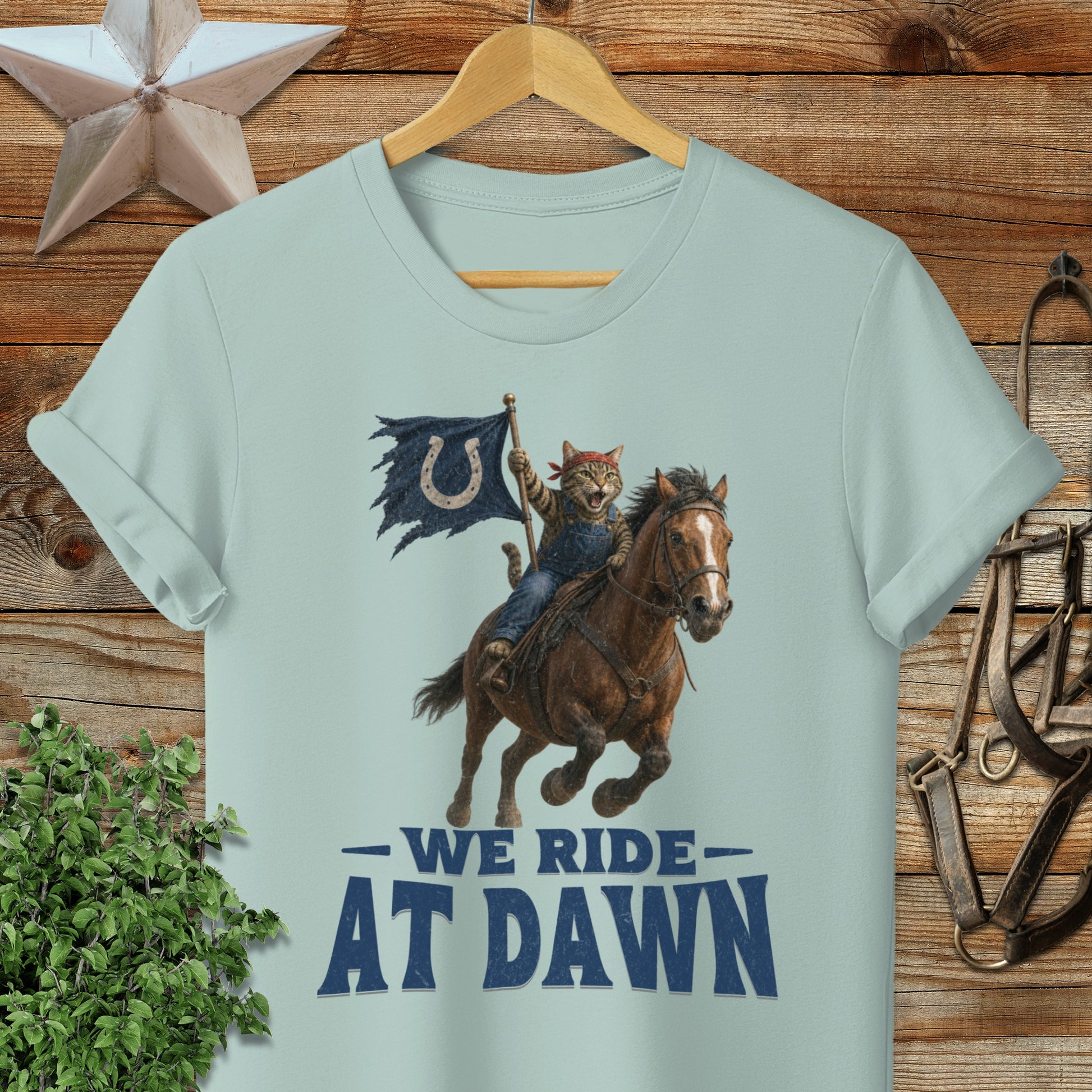 Cat cowboy riding horse with flag, "We Ride At Dawn" text.