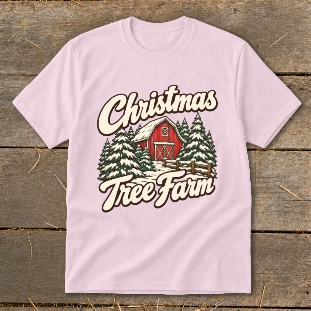 Light pink t-shirt with a Christmas tree farm graphic featuring a red barn and snow.