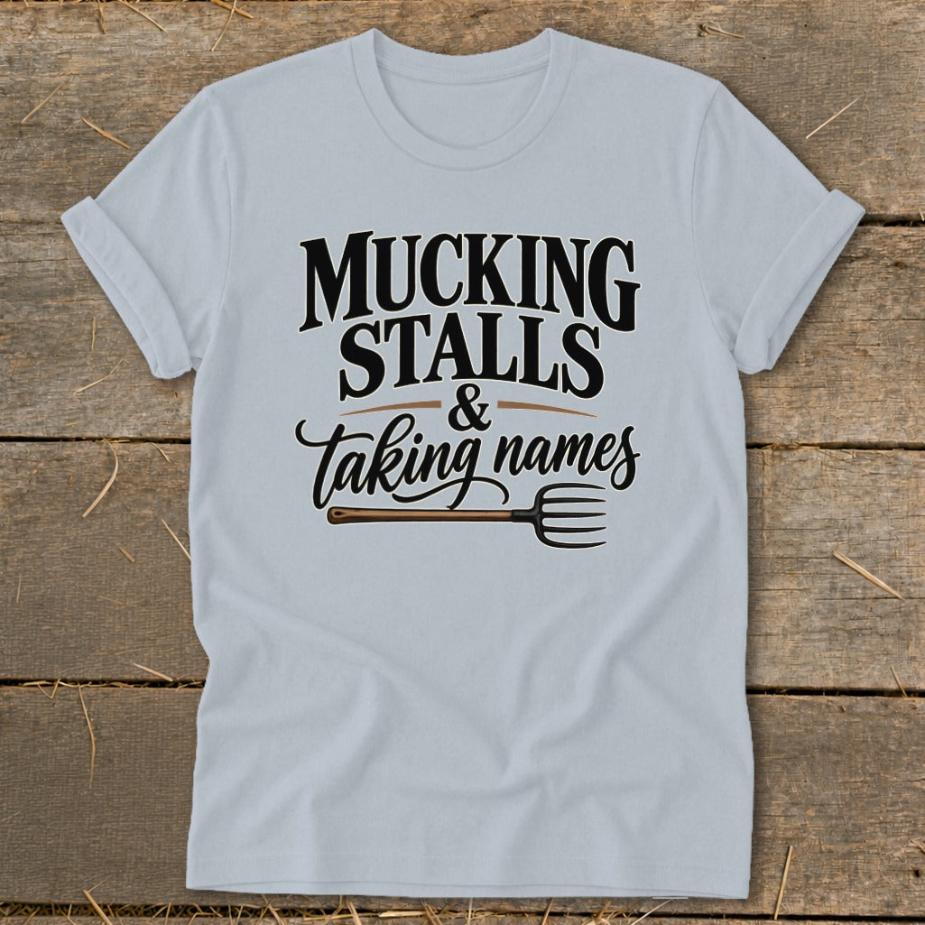 Light blue t-shirt with text "Mucking Stalls & Taking Names" and a pitchfork graphic.