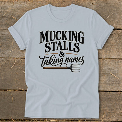 Light blue t-shirt with text "Mucking Stalls & Taking Names" and a pitchfork graphic.