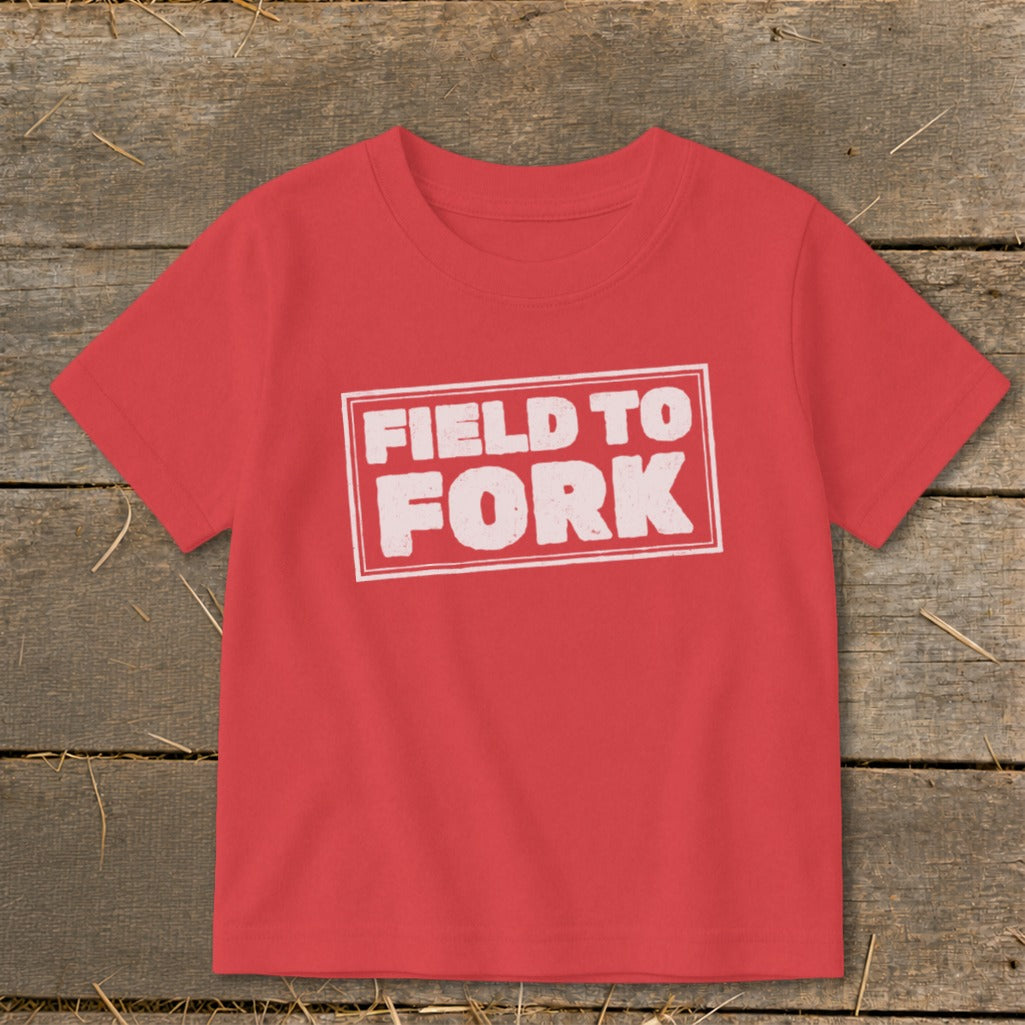 A red short-sleeve t-shirt with the text FIELD TO FORK printed in a white distressed rectangle.