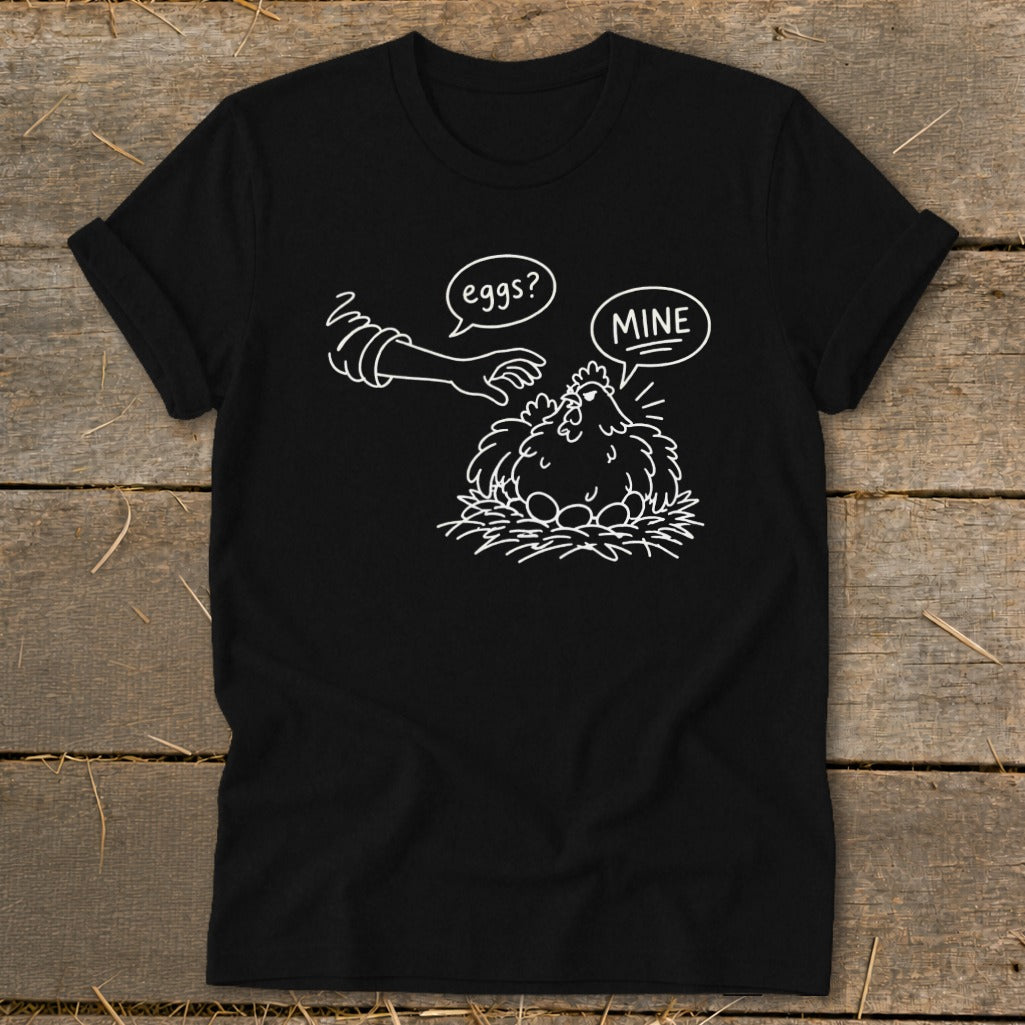 Black t-shirt with cartoon chicken guarding eggs, text "eggs?" and "MINE".