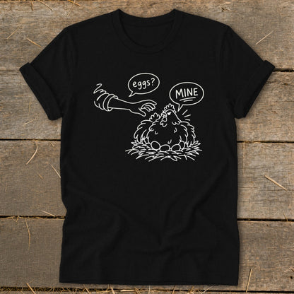 Black t-shirt with cartoon chicken guarding eggs, text "eggs?" and "MINE".