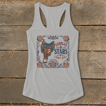 Grey tank top with a western saddle design featuring American flag stars and text "Saddles & Stars Since 1776".