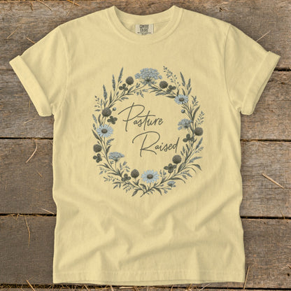 Light yellow t-shirt with a floral wreath and "Pasture Raised" text.