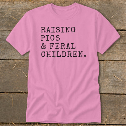 Pink t-shirt with black text: "RAISING PIGS & FERAL CHILDREN."