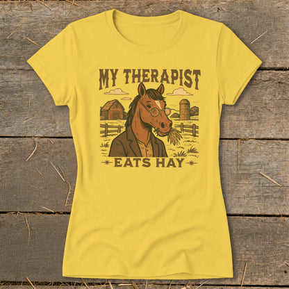 Yellow t-shirt with a horse wearing glasses and eating hay, text reads "My Therapist Eats Hay".
