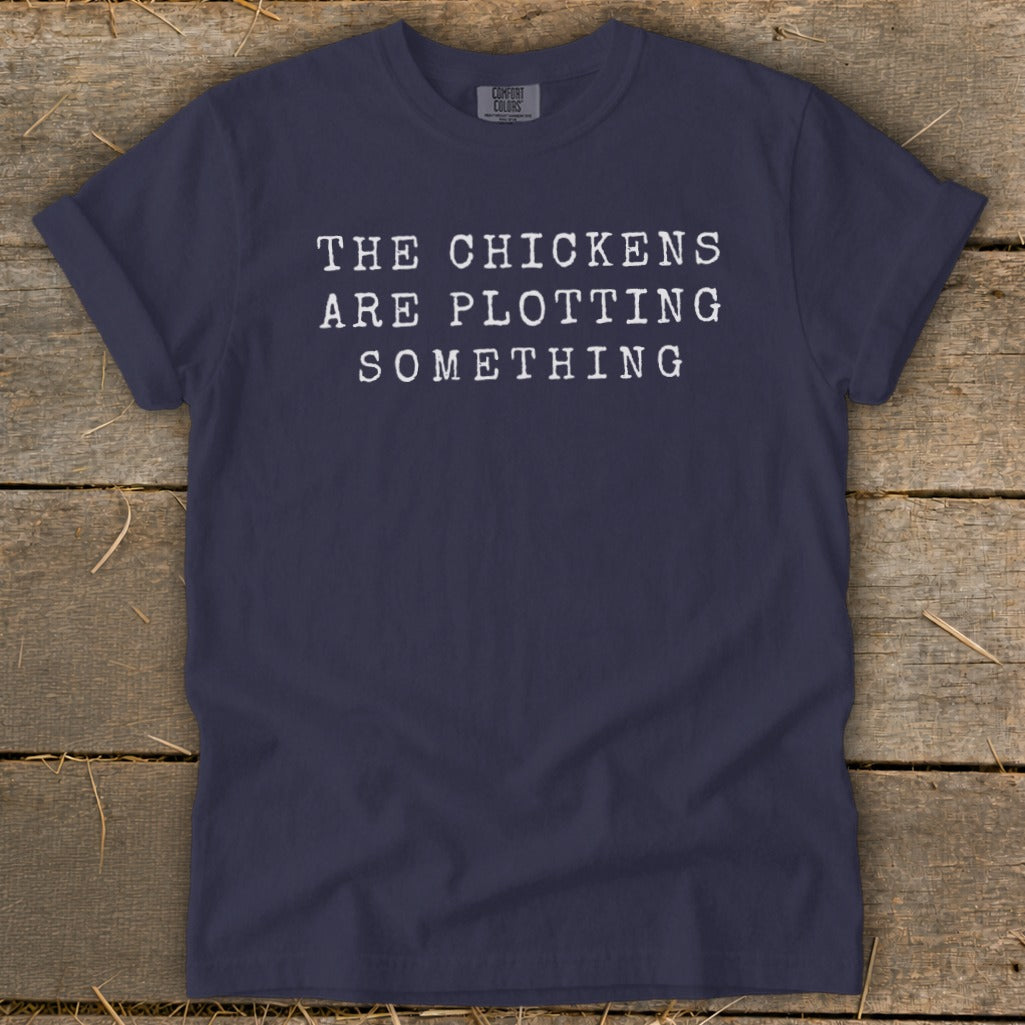 Navy t-shirt with white text reading "THE CHICKENS ARE PLOTTING SOMETHING".