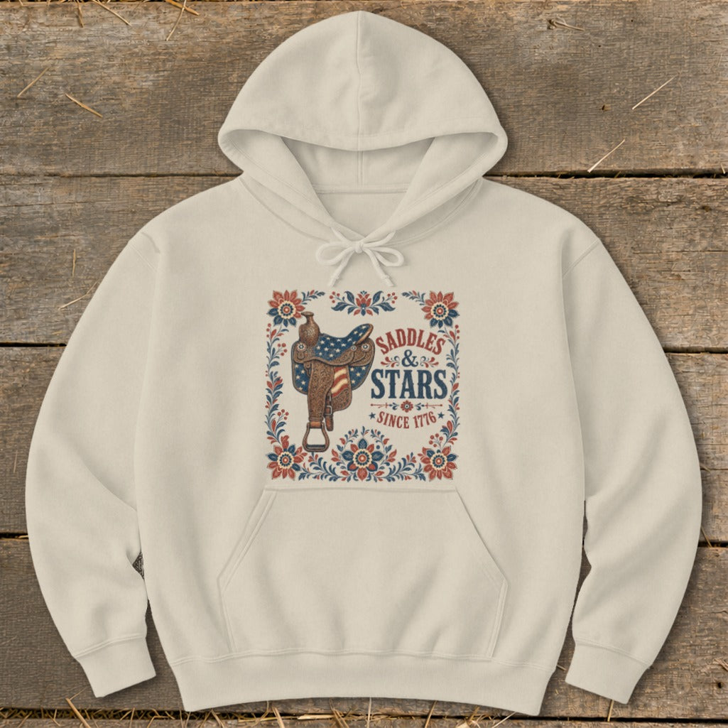 Cream hoodie with a "Saddles & Stars Since 1776" graphic featuring a saddle with American flag details.