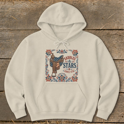 Cream hoodie with a "Saddles & Stars Since 1776" graphic featuring a saddle with American flag details.