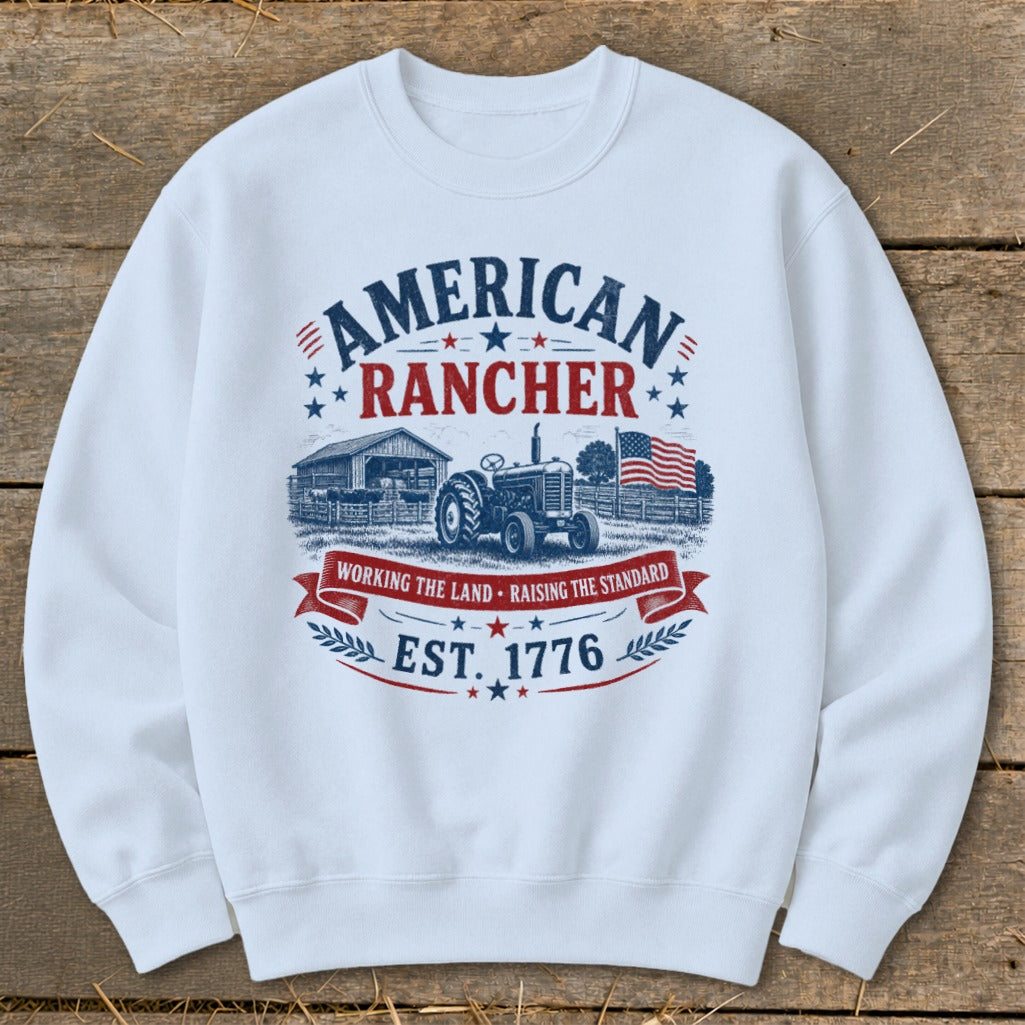 White sweatshirt with "American Rancher" graphic, tractor, barn, and American flag.