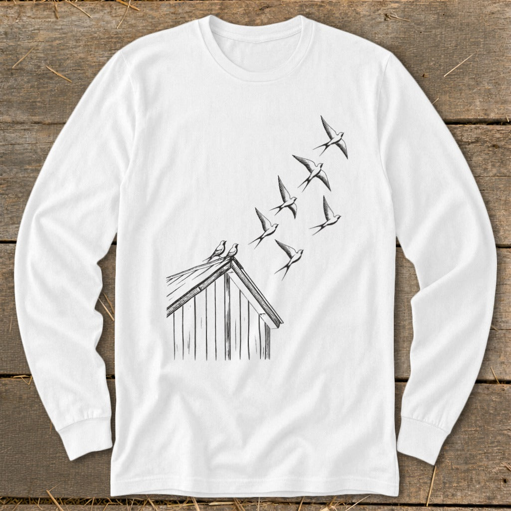 A white long-sleeve t-shirt features a black line drawing of swallows flying up from a barn roof.