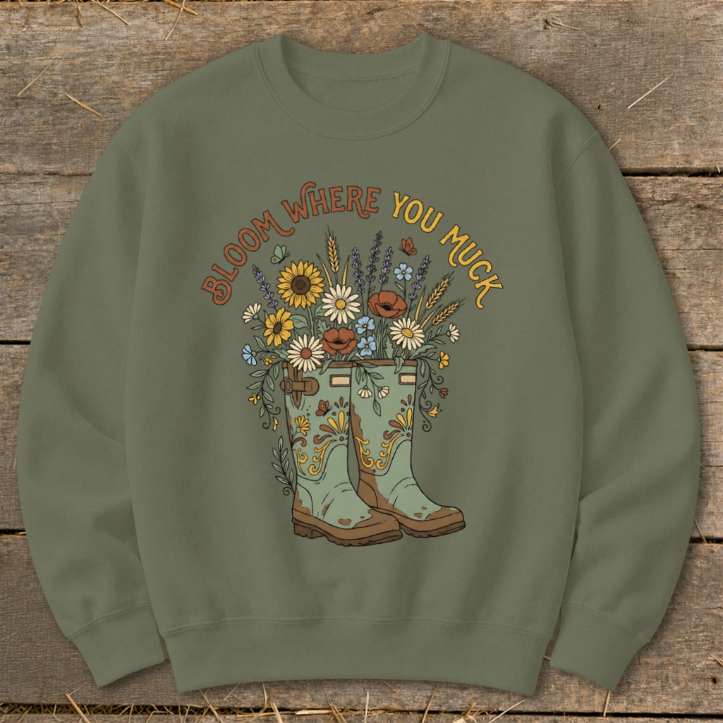 Green sweatshirt with "Bloom Where You Muck" text and floral gardening boots graphic.
