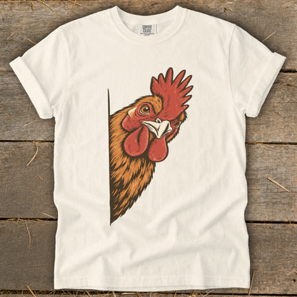 Illustration of a rooster's head peeking from the side of a cream t-shirt.