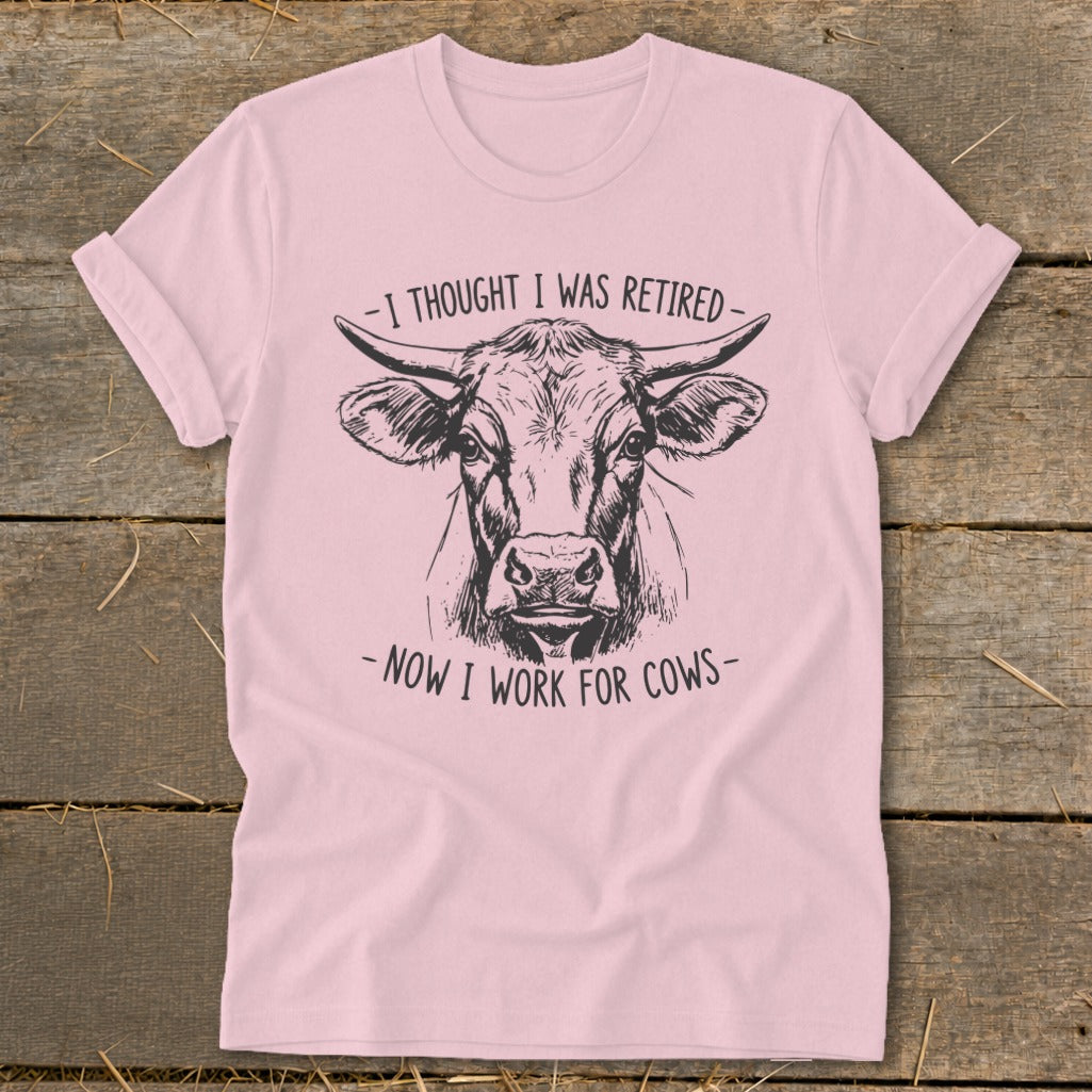 Pink t-shirt with a sketch of a cow's head and text saying "I thought I was retired - Now I work for cows".