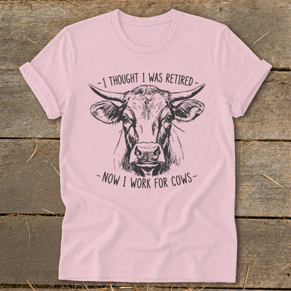 Pink t-shirt with a sketch of a cow's head and text saying "I thought I was retired - Now I work for cows".