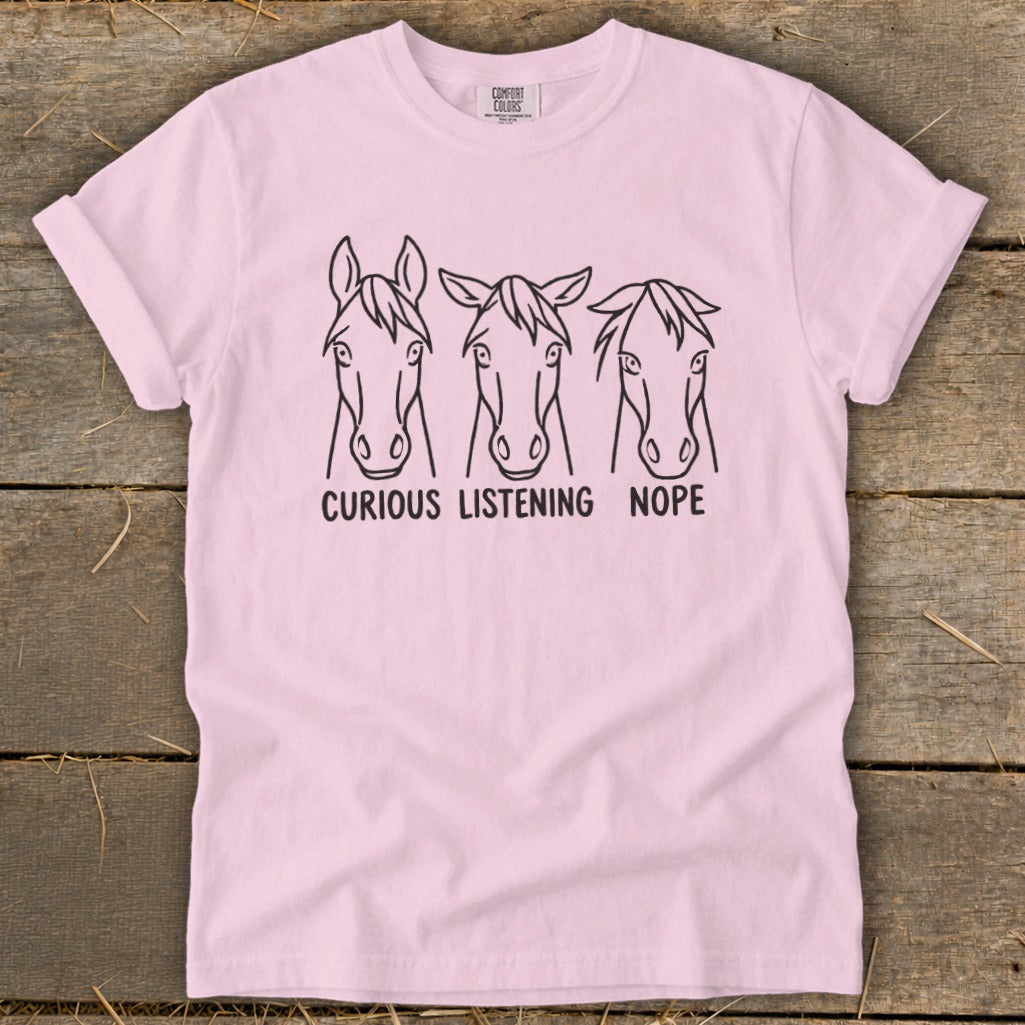 Light pink t-shirt featuring three horse head illustrations with the captions Curious, Listening, and Nope.