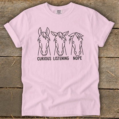 Light pink t-shirt featuring three horse head illustrations with the captions Curious, Listening, and Nope.