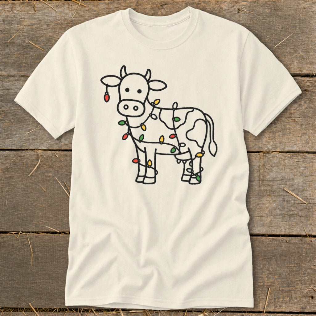 Cream t-shirt with a black outline drawing of a cow wrapped in colorful Christmas lights.