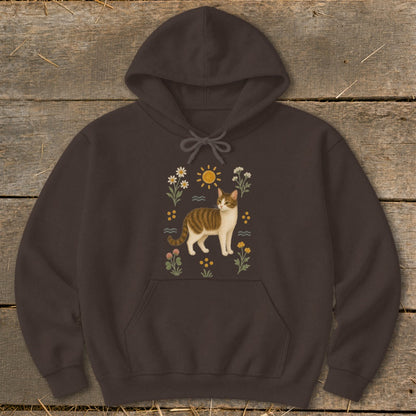 Brown hoodie with a brown and white cat amidst flowers and a sun graphic.