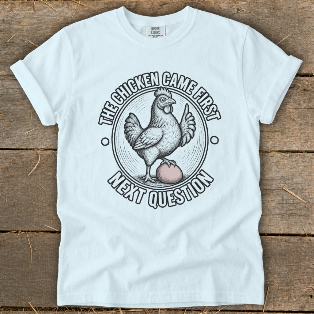 White t-shirt with a chicken and egg graphic and text "The chicken came first. Next question."