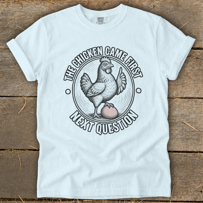 White t-shirt with a chicken and egg graphic and text "The chicken came first. Next question."