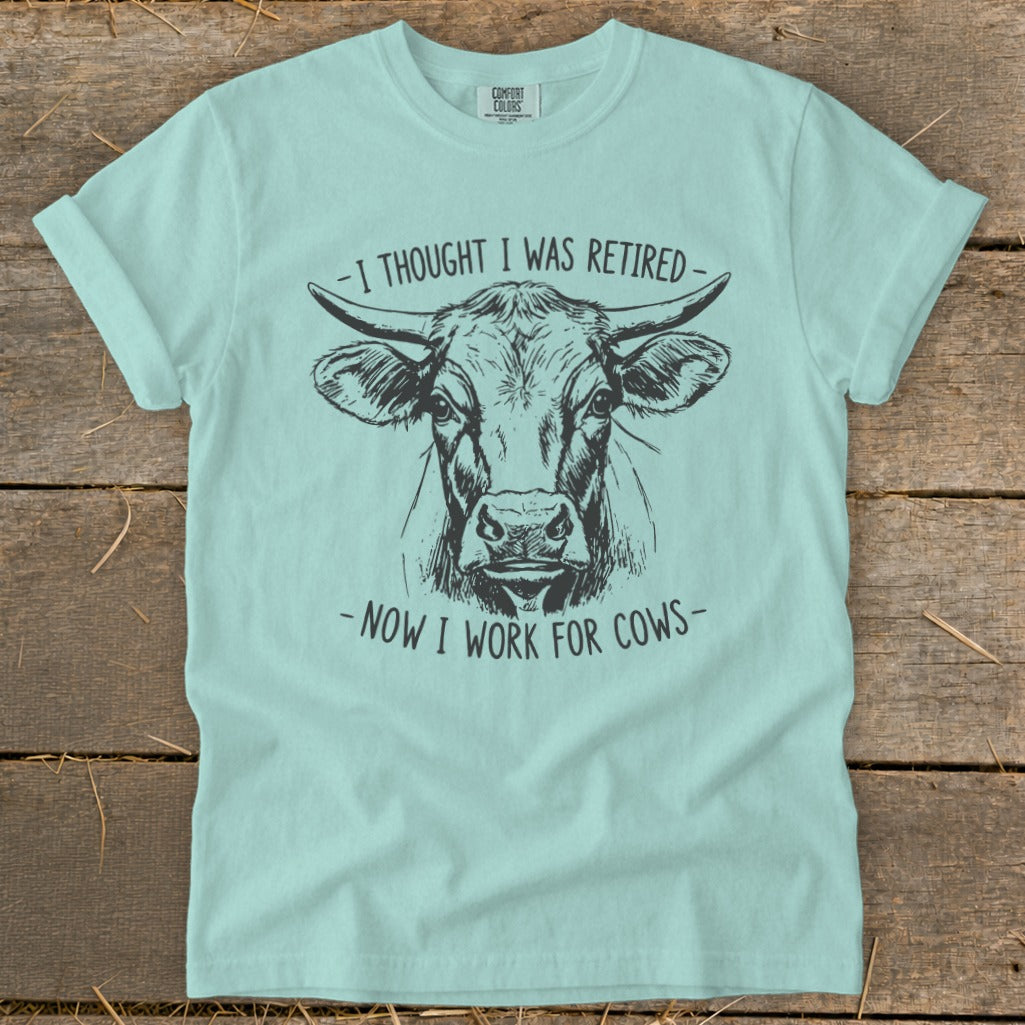 Light blue t-shirt with cow art and text "I thought I was retired - now I work for cows."