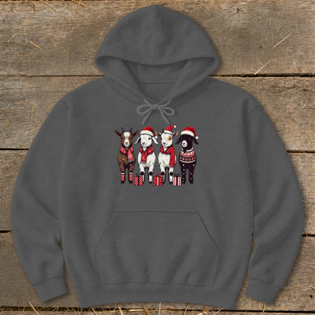 Four goats in Christmas hats and scarves stand with gifts on a dark gray hoodie.