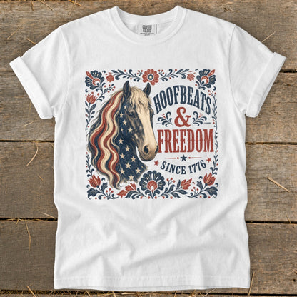 White t-shirt with a horse graphic and text "Hoofbeats & Freedom Since 1776".