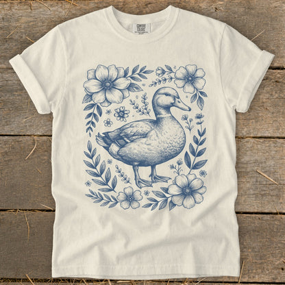 Cream t-shirt with blue duck and floral illustration.
