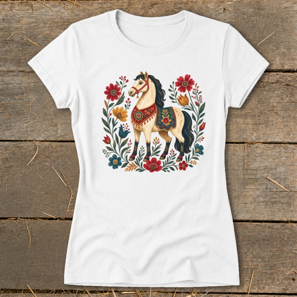White t-shirt with a cream-colored horse adorned in a colorful blanket, surrounded by floral accents.