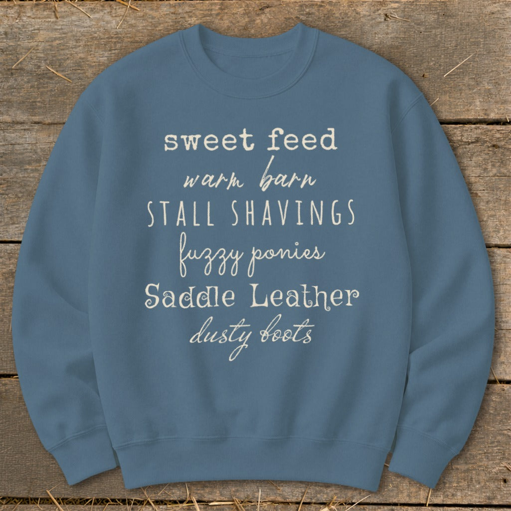 Blue sweatshirt with text: sweet feed, warm barn, STALL SHAVINGS, fuzzy ponies, Saddle Leather, dusty boots.