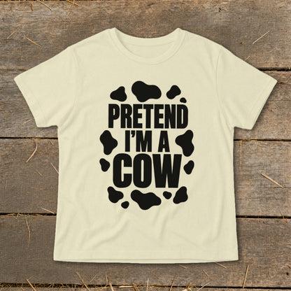 Cream t-shirt with black text "PRETEND I'M A COW" and cow spots.