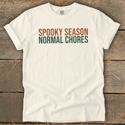 Cream t-shirt with "SPOOKY SEASON NORMAL CHORES" text in brown and green.