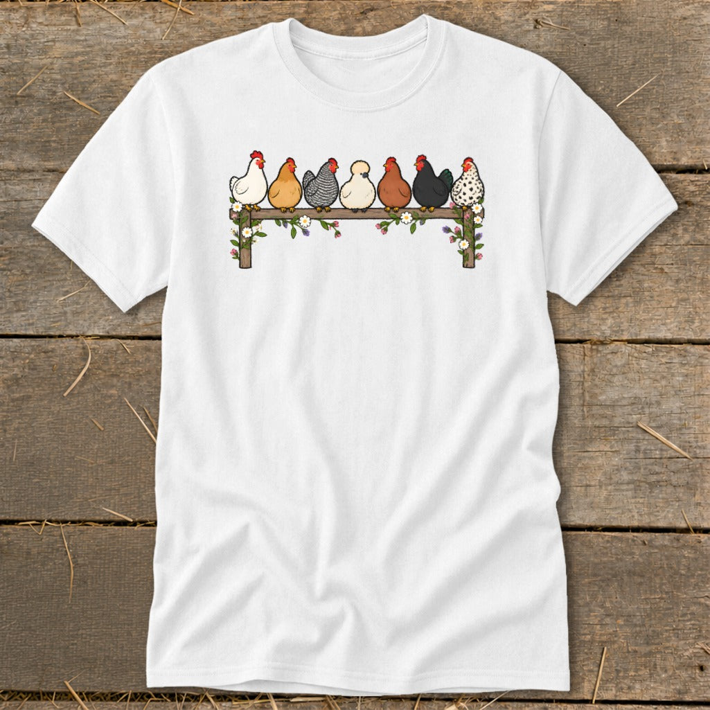 A white short-sleeved t-shirt featuring an illustration of seven colorful chickens perched on a flower-decorated wooden fence.