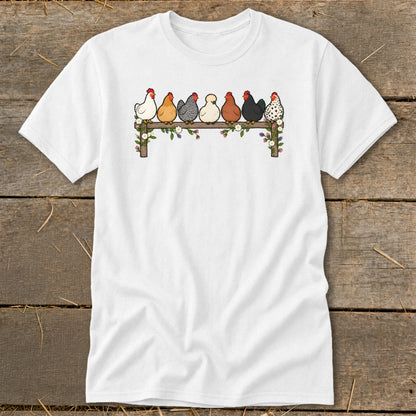A white short-sleeved t-shirt featuring an illustration of seven colorful chickens perched on a flower-decorated wooden fence.