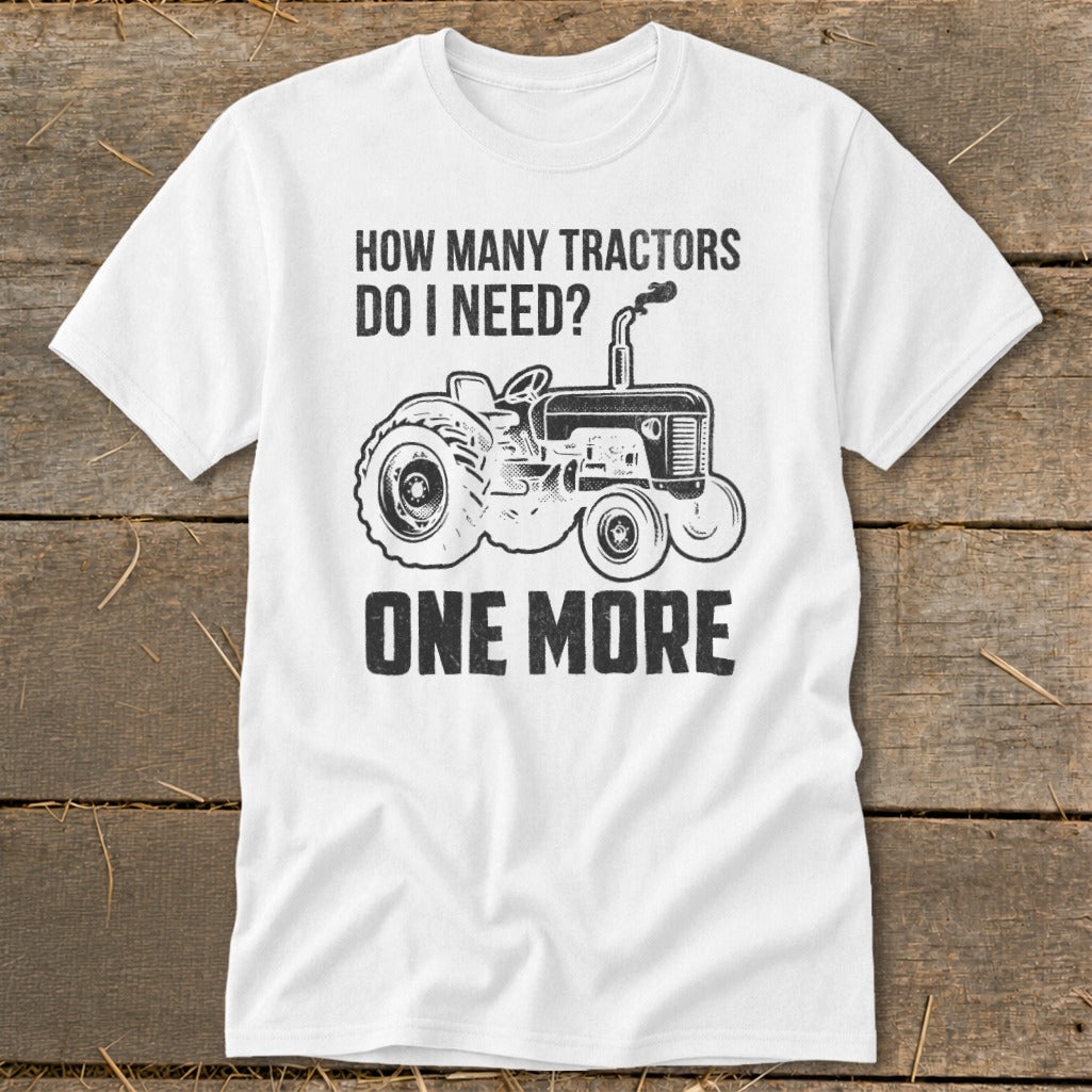 White t-shirt with tractor graphic and text "How many tractors do I need? One More".
