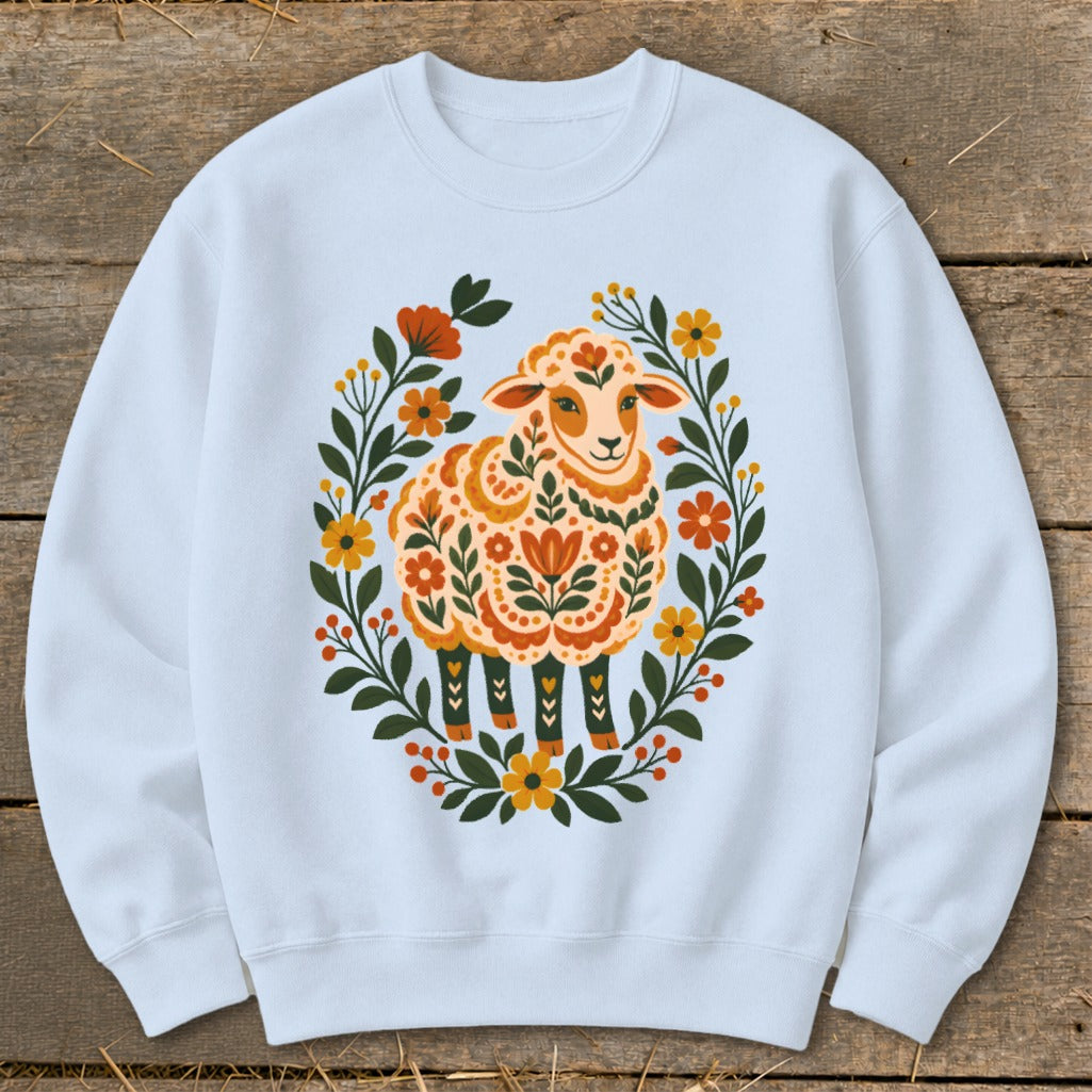 Light blue sweatshirt with a folk-art style sheep illustration surrounded by a floral wreath.