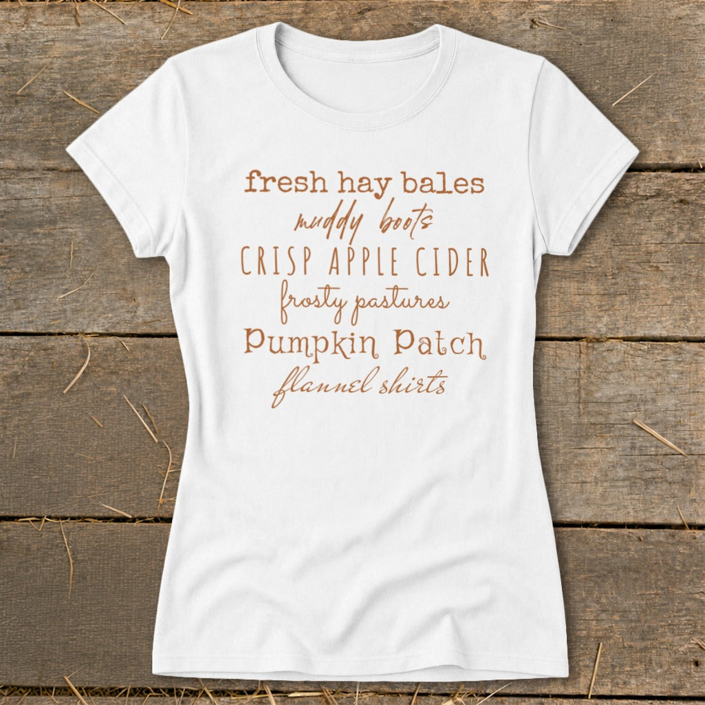 White t-shirt with list of fall activities: hay bales, muddy boots, apple cider, pastures, pumpkin patch, flannel shirts.