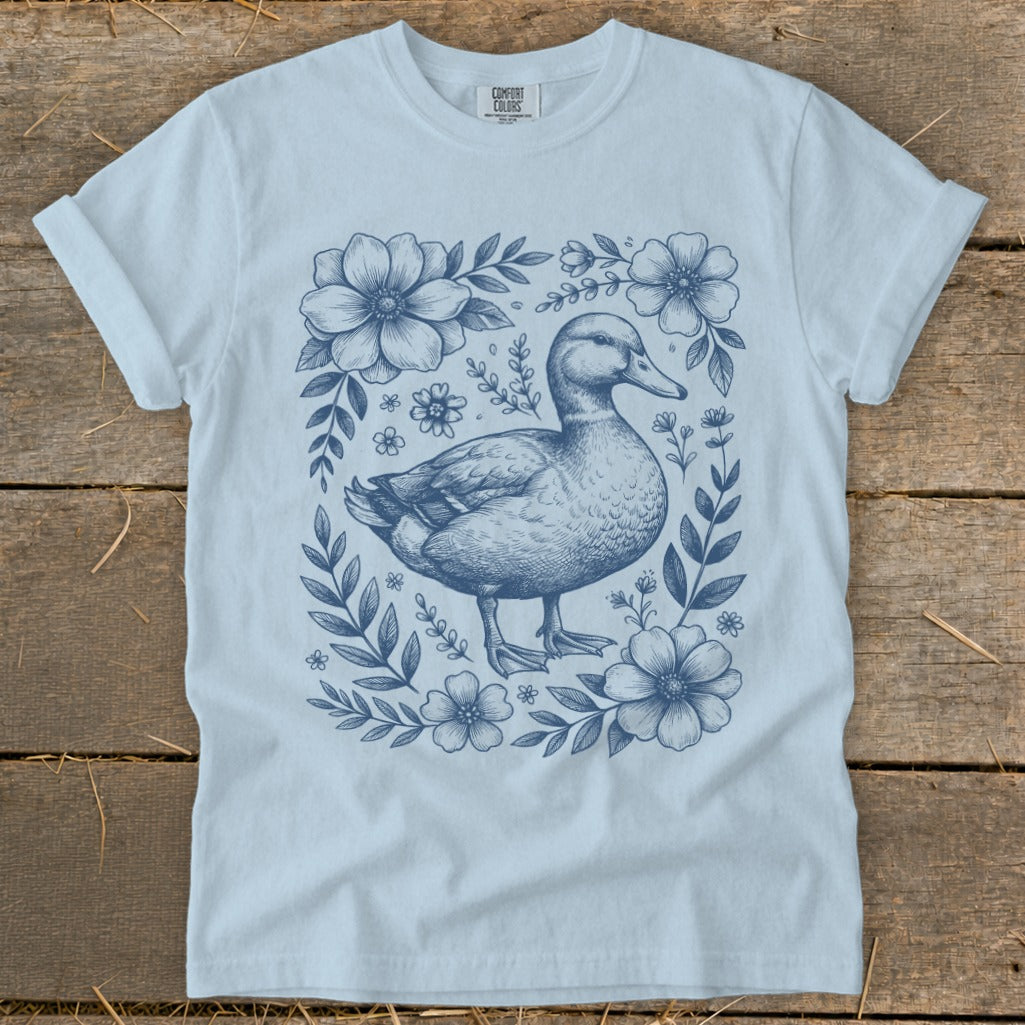 Light blue t-shirt with a blue sketch of a duck surrounded by flowers.
