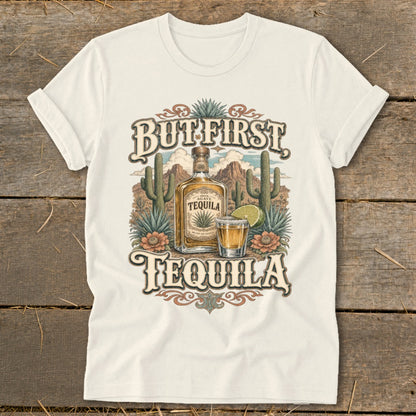 Cream t-shirt with "But First Tequila" graphic featuring a tequila bottle, shot glass, cacti, and desert landscape.