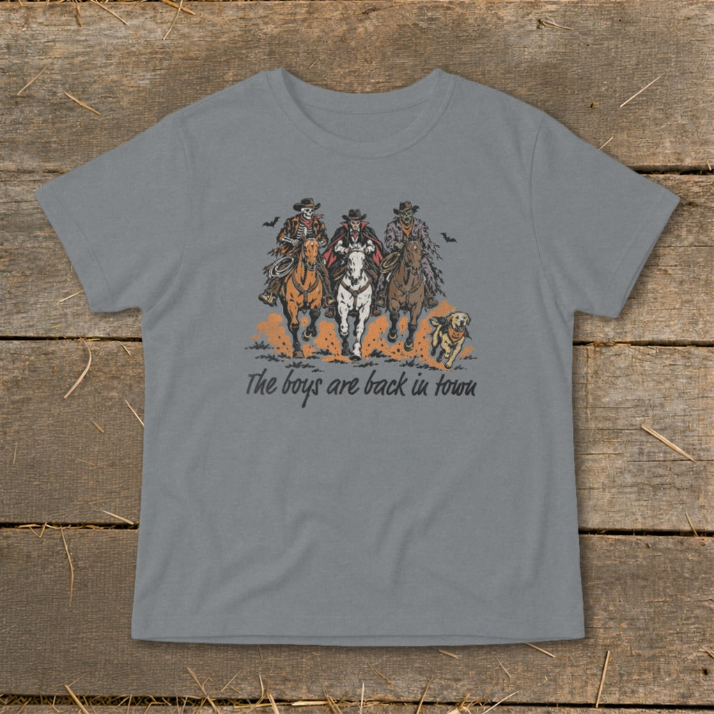 Three costumed figures on horses with a dog, text reads "The boys are back in town".
