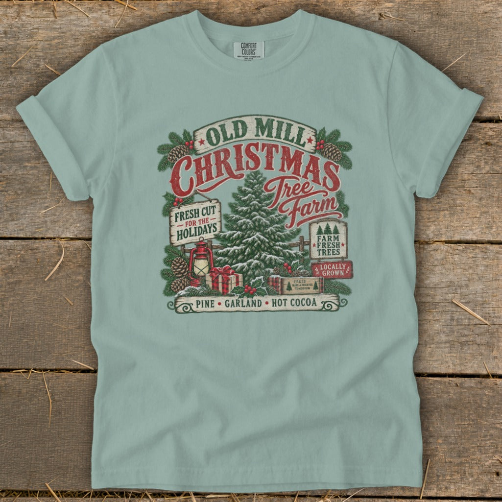 T-shirt with Old Mill Christmas Tree Farm graphic featuring pine trees, gifts, and lantern.