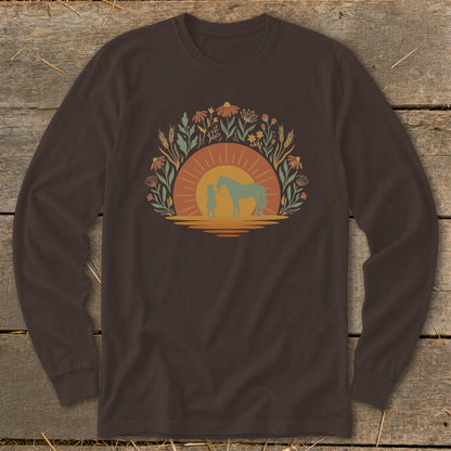 Silhouette of a person with a horse against a sunset and floral border.