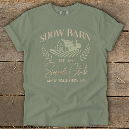 Sage green t-shirt with "Show Barn Social Club" graphic, featuring barn and fields.
