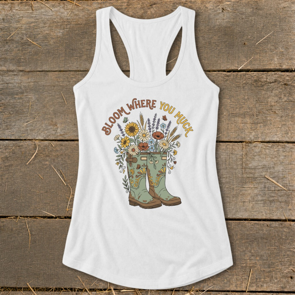 White tank top with green boots and flowers, "Bloom Where You Muck" text.